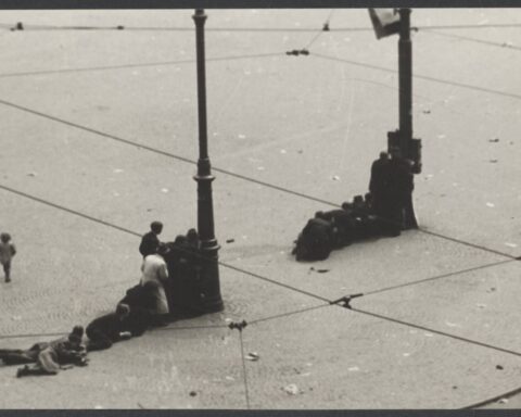 Mensen zoeken dekking op de Dam. Links loopt een een klein meisje over het plein.